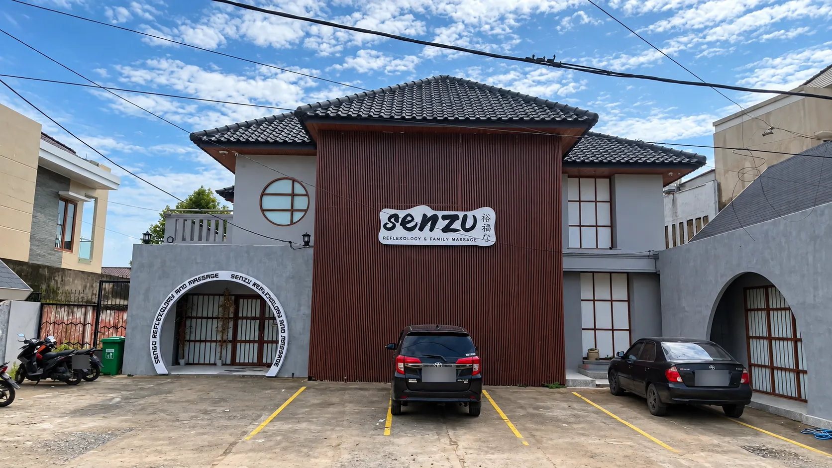 Fasad Senzu: bangunan dua lantai beratap genteng gelap dengan dinding kayu, papan nama Senzu, dan gerbang lengkung